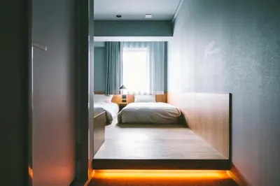 a bedroom with a bed and a window and a mirror at LANDABOUT TOKYO in Tokyo