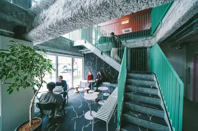 a room with stairs and people sitting at tables at LANDABOUT TOKYO in Tokyo