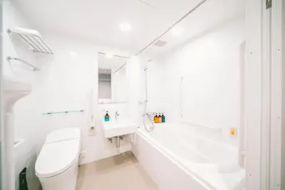 a white bathroom with a toilet and a sink at LANDABOUT TOKYO in Tokyo