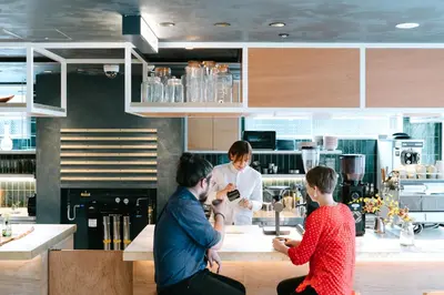 a group of people sitting at a counter in a kitchen at LANDABOUT TOKYO in Tokyo