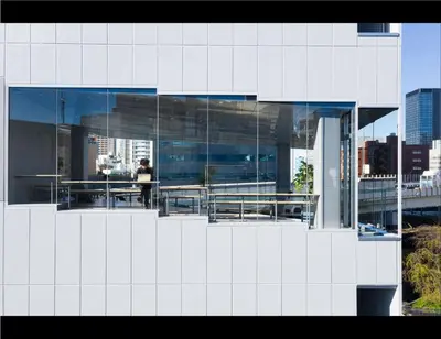 a white building with a person standing on a balcony at 9h nine hours Suidobashi in Tokyo