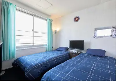 two beds in a bedroom with blue sheets and a tv at 2BR 5beds Shibuya Shinjuku Harajuku 10min wifi in Tokyo