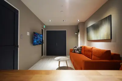 a living room with an orange couch and a table at Real Life Meguro River in Tokyo