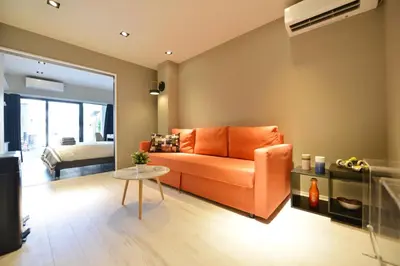 an orange couch in a living room with a bedroom at Real Life Meguro River in Tokyo