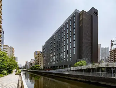 a building next to a river in a city at Shizutetsu Hotel Prezio Tokyo Tamachi in Tokyo
