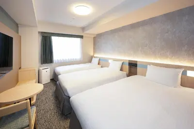 a hotel room with two beds and a table at Hotel Lumiere Nishikasai in Tokyo