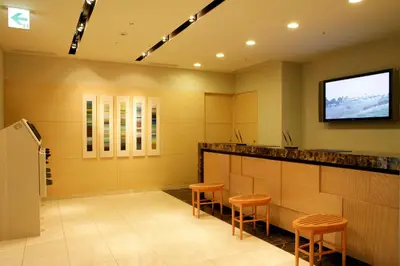 a waiting room with stools and a television on the wall at Hotel Lumiere Nishikasai in Tokyo