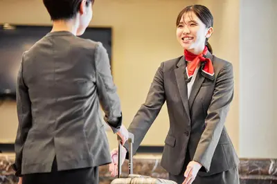 a woman in a suit shaking hands with a man at Hotel Lumiere Kasai in Tokyo