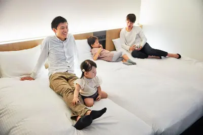 a group of people sitting on a bed at Hotel Lumiere Kasai in Tokyo