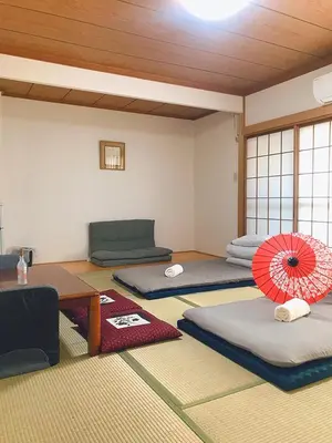 a room with four beds and a red umbrella at ohayo\u672c\u6240 in Tokyo