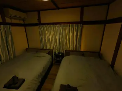 a bedroom with two beds and a window at SquareHouse Nishiarai in Tokyo