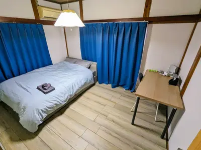 a bedroom with a bed and a desk and blue curtains at SquareHouse Nishiarai in Tokyo