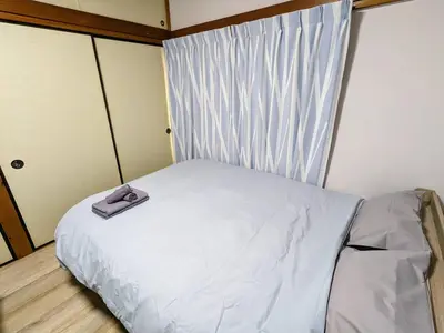 a small bed in a room with a window at SquareHouse Nishiarai in Tokyo