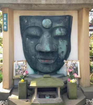 a large statue of a face on a wall at Ueno Garden House - 2 mins walk to subway, 2 mins train to Akihabara, 2 mins train to Asakusa in Tokyo