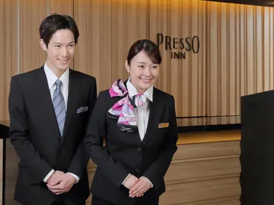 two people in suits posing for a picture at Keio Presso Inn Otemachi in Tokyo