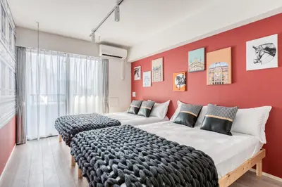 two beds in a room with a red wall at Ostay Nippori Hotel Apartment (Nishi-Nippori Sta.) in Tokyo