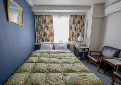 a bedroom with a bed and a chair and a window at Hotel Koryukaku in Tokyo