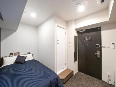 a small bedroom with a bed and a door at HOTEL LiVEMAX Asakusa-Ekimae in Tokyo