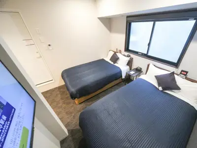 a hotel room with two beds and a tv at HOTEL LiVEMAX Asakusa-Ekimae in Tokyo