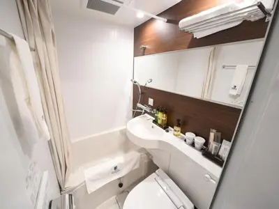 a bathroom with a toilet and a sink and a mirror at HOTEL LiVEMAX Asakusa-Ekimae in Tokyo