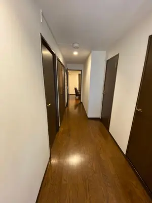 an empty hallway with doors and a wooden floor at Residential Hotel Bevel Tokyo in Tokyo