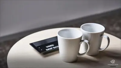 two white coffee mugs and a cell phone on a table at Daiwa Roynet Hotel Tokyo Kyobashi PREMIER in Tokyo