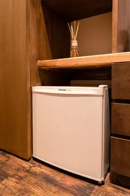 a small white refrigerator sitting in a kitchen at \u90fd\u96fb\u5c4b TodenHotel in Tokyo