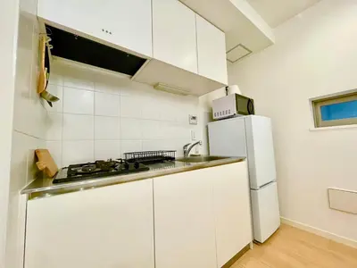 a white kitchen with a sink and a refrigerator at SALON Shibuya in Tokyo