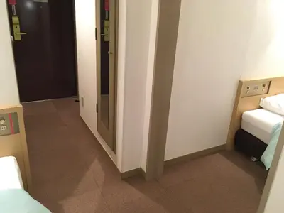a small room with two beds and a doorway at Olympic Inn Azabu in Tokyo