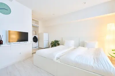 a white bedroom with a large bed and a flat screen tv at STAY ARI Arakicho in Tokyo
