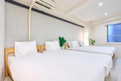 two beds in a room with white sheets at STAY ARI Arakicho in Tokyo