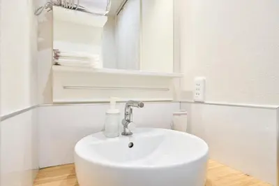 a white bathroom with a sink and a mirror at STAY ARI Arakicho in Tokyo