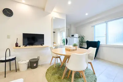 a dining room and living room with a table and chairs at STAY ARI Arakicho in Tokyo