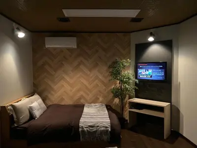 a bedroom with a bed and a tv on a wall at HOTEL Japonica in Tokyo