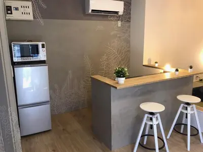 a kitchen with a counter with stools and a refrigerator at HOTEL Japonica in Tokyo