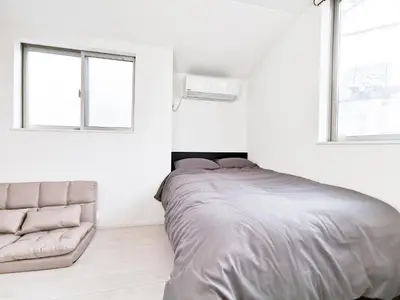 a white bedroom with a bed and a couch at Private Hotel Oshiage in Tokyo