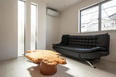 a living room with a black leather couch and a wooden table at Private Hotel Oshiage in Tokyo