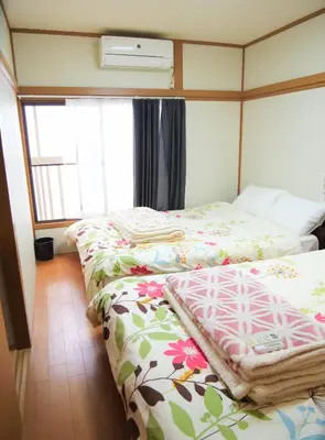 a bedroom with two beds with floral sheets and a window at \u9326\u306e\u9928 Nishiki\u306eYakata in Tokyo