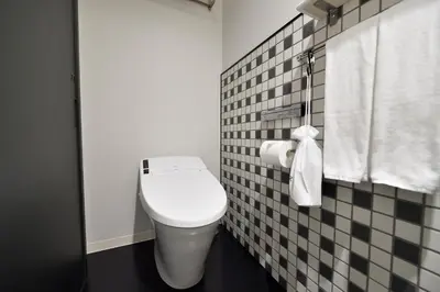 a white toilet in a bathroom with black and white tiles at HOTEL TAVINOS Asakusa in Tokyo