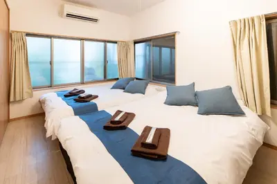 a room with two large beds with chairs and windows at \u96fb\u8eca\u3067\u79cb\u8449\u539f\u99c511\u5206 \u6771\u4eac\u99c518\u5206 \u5e73\u4e95\u99c5\u5f92\u6b698\u5206 in Tokyo