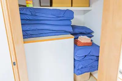 a stack of blue pillows in a closet at \u96fb\u8eca\u3067\u79cb\u8449\u539f\u99c511\u5206 \u6771\u4eac\u99c518\u5206 \u5e73\u4e95\u99c5\u5f92\u6b698\u5206 in Tokyo