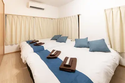 two large white beds in a room with blue pillows at \u96fb\u8eca\u3067\u79cb\u8449\u539f\u99c511\u5206 \u6771\u4eac\u99c518\u5206 \u5e73\u4e95\u99c5\u5f92\u6b698\u5206 in Tokyo