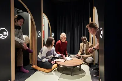 a group of people sitting around a table in a room at Resol Poshtel Tokyo Asakusa in Tokyo