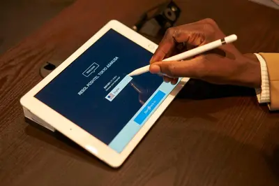 a person holding a white pen on top of a tablet at Resol Poshtel Tokyo Asakusa in Tokyo