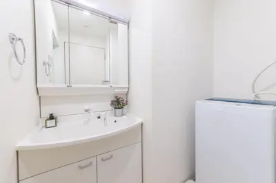 a white bathroom with a sink and a refrigerator at SHINJUKU Residence BLDG in Tokyo