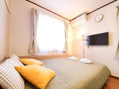 a bedroom with a bed and a tv on the wall at nestay suite tokyo shibuya in Tokyo