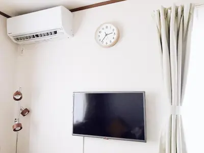 a tv and a clock on a white wall at nestay suite tokyo shibuya in Tokyo