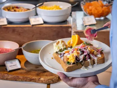 a person holding a plate of food on a table at YADOYA Uguisu in Tokyo