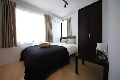 a bedroom with a bed and a table and a window at CORDEA\u516b\u5e83 in Tokyo