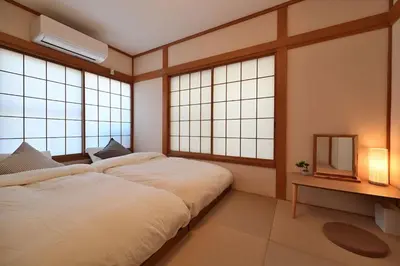 a bedroom with a large bed and two windows at OMM STAY in Tokyo
